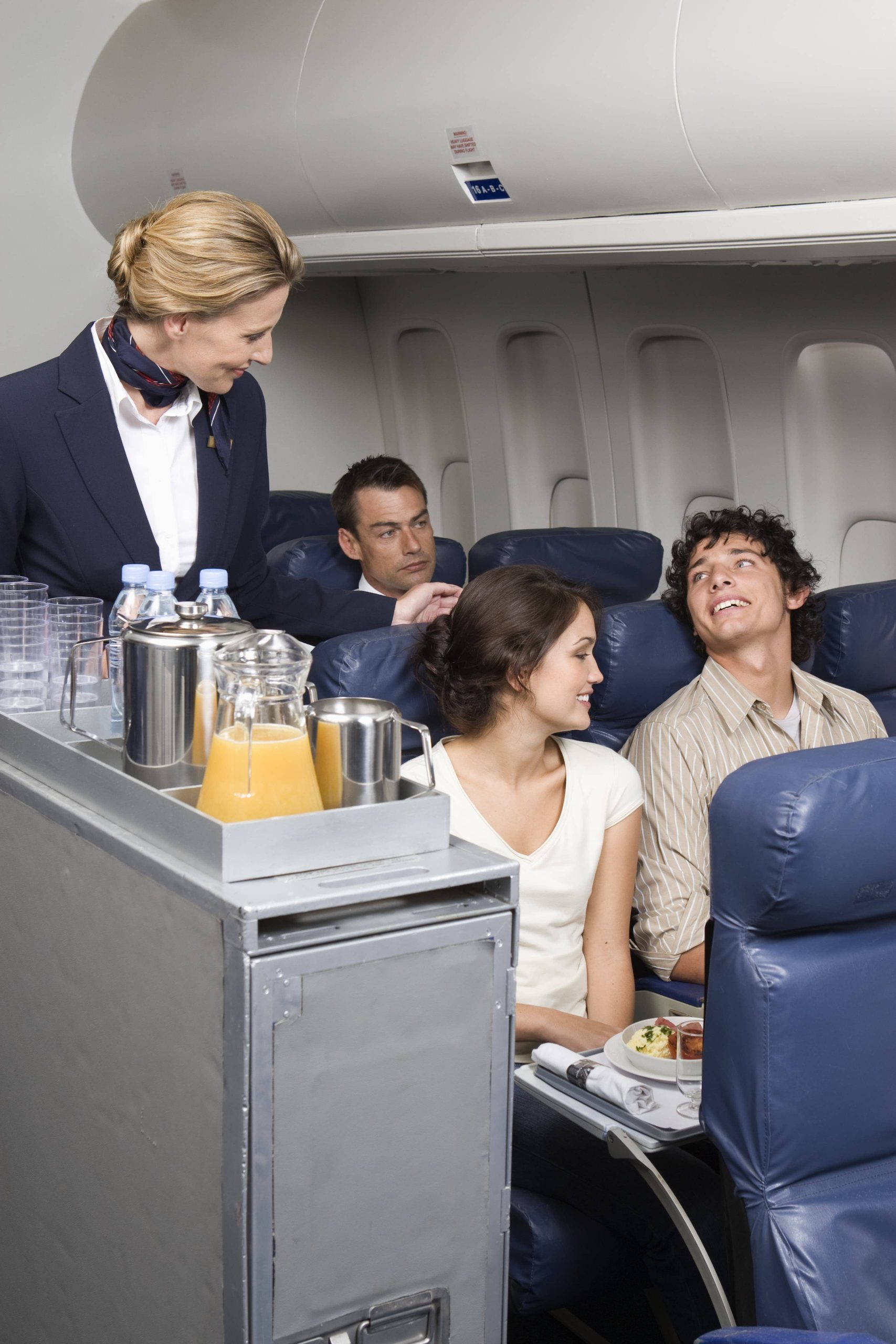 Female flight attendant serving drink to passenger